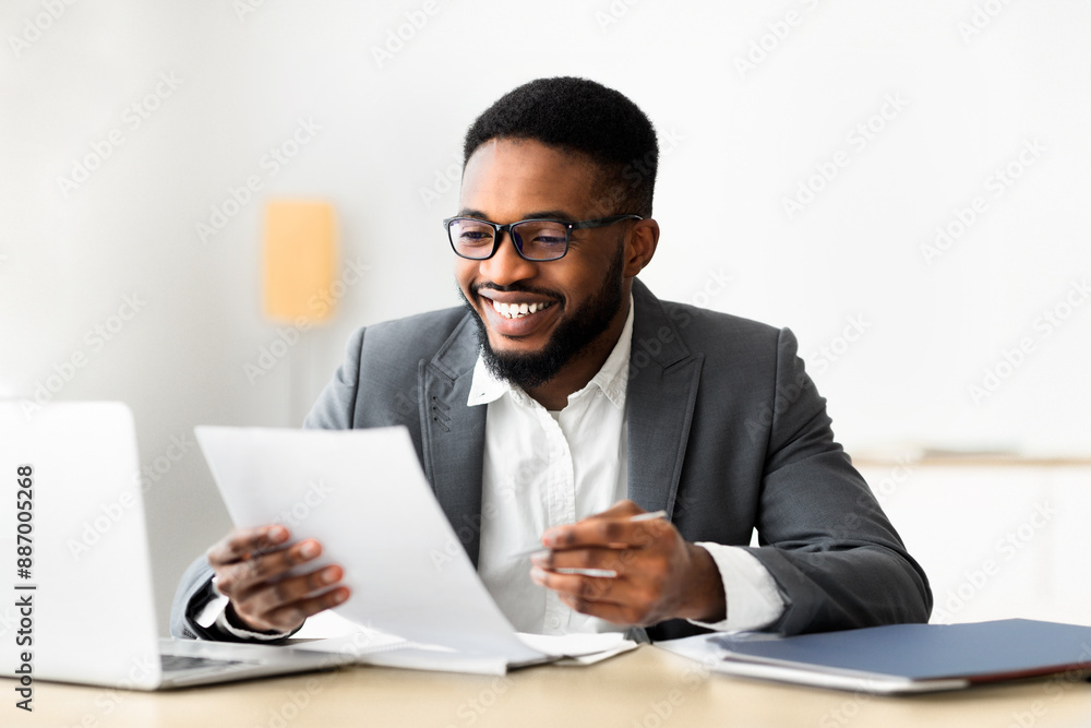 Cheerful african american businessman checking reports and making notes, copy space Cheerful african american businessman checking reports and making notes, copy space