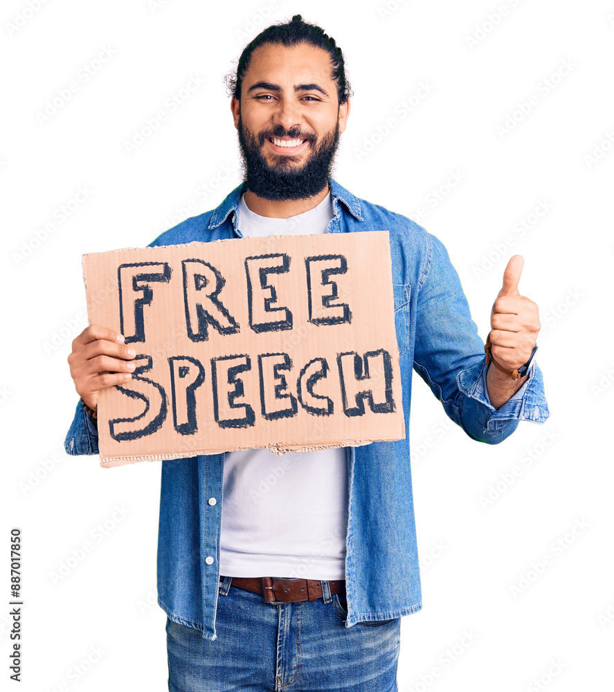 Young arab man holding free speech banner smiling happy and positive, thumb up doing excellent and approval sign Young arab man holding free speech banner smiling happy and positive, thumb up doing excellent and approval sign