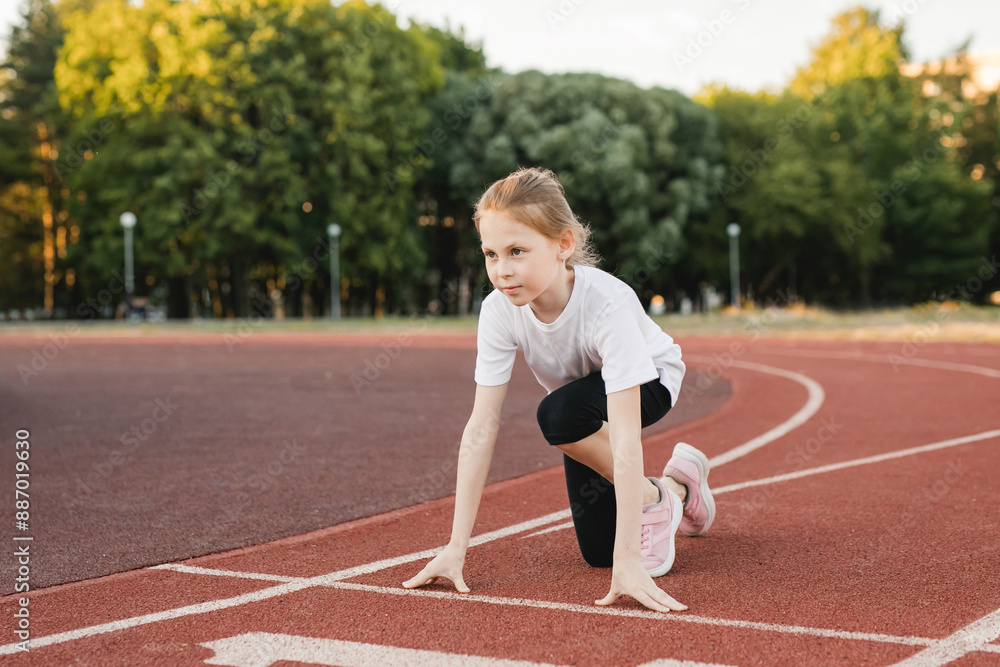 Fototapeta premium Child girl track athlete at starting block. Sport, healthy lifestyle, physical education.