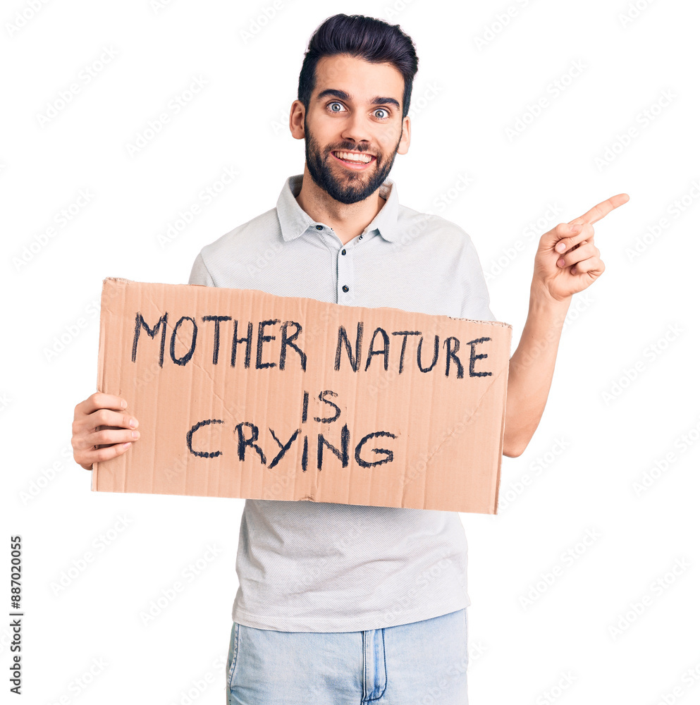Young handsome man with beard holding mother nature is crying cardboard banner smiling happy pointing with hand and finger to the side Young handsome man with beard holding mother nature is crying cardboard banner smiling happy pointing with hand and finger to the side