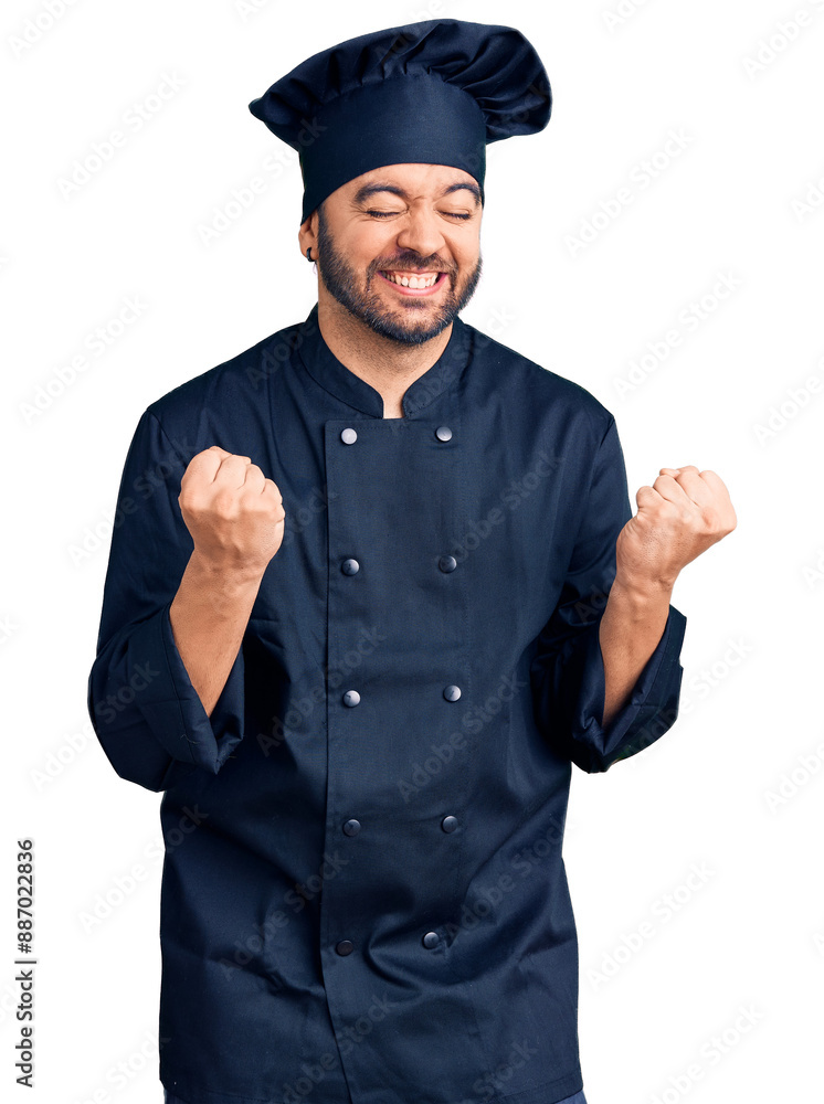 Young hispanic man wearing cooker uniform excited for success with arms raised and eyes closed celebrating victory smiling. winner concept. Young hispanic man wearing cooker uniform excited for success with arms raised and eyes closed celebrating victory smiling. winner concept.