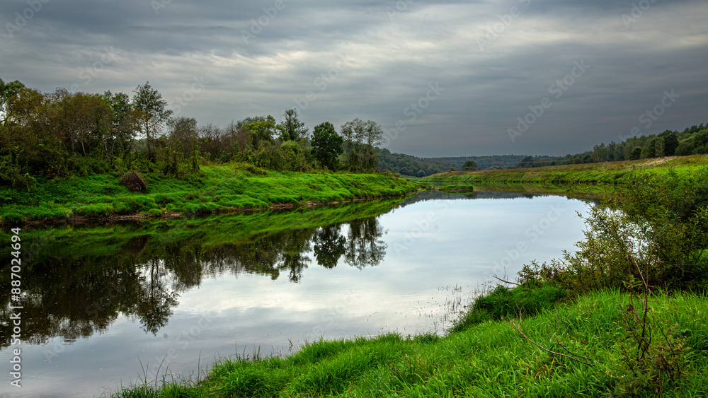 Enjoy the serene river landscape with reflective water and lush greenery in a natural environment Enjoy the serene river landscape with reflective water and lush greenery in a natural environment