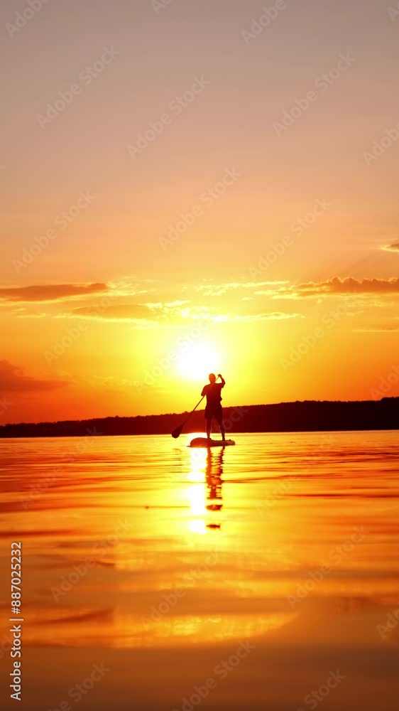 Amazing sunset on the calm river in summer with man practicing sup boarding. Doing paddle board sport in the nature. Low angle view. Vertical video. Amazing sunset on the calm river in summer with man practicing sup boarding. Doing paddle board sport in the nature. Low angle view. Vertical video.