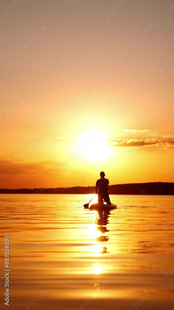 Sportsman standing on his knees on the sup board moves by the river. Man rows with an oar at sunset. Low angle view. Vertical video. Sportsman standing on his knees on the sup board moves by the river. Man rows with an oar at sunset. Low angle view. Vertical video.