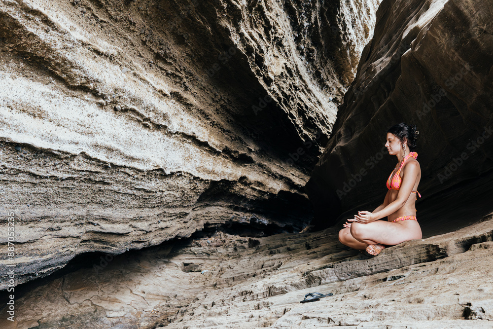 Woman meditating in serene rocky cave on summer holiday Woman meditating in serene rocky cave on summer holiday