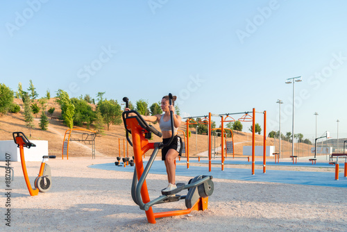 Young woman exercises on outdoor fitness equipment photo