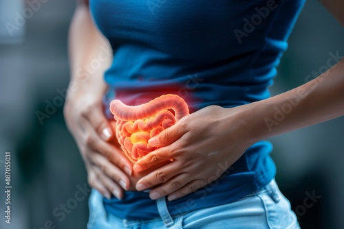 Woman holds with both hands the area of the gut illuminated in 3D with the intestine photo