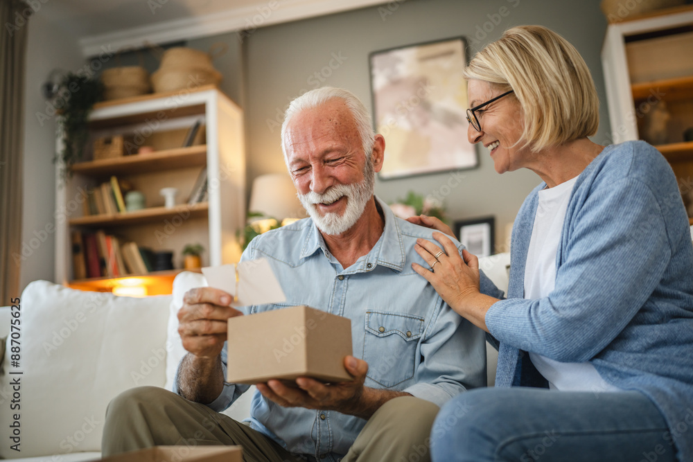 Senior husband read greeting card from a gift with his mature wife Senior husband read greeting card from a gift with his mature wife