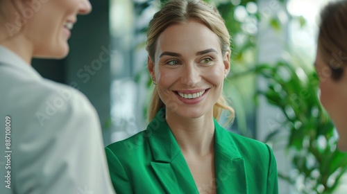 A young happy businesswoman in a refreshing green outfit meets with her colleagues in the office, showcasing teamwork and positivity