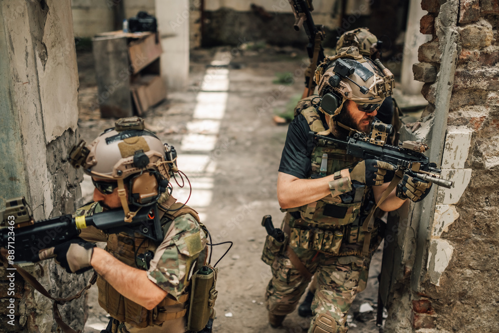 Obraz premium Group of air soft soldiers going in a battle in ruined building.