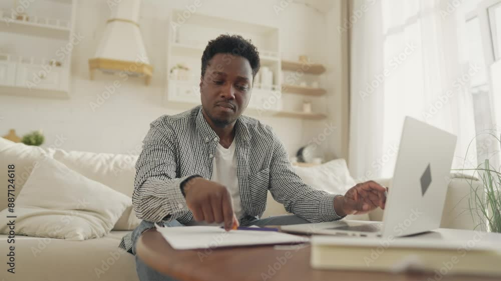 Freelancer working with computer in home workplace, making notes in to do list. Portrait of young adult black man using laptop for work, education or entertainment, African male person in cozy room Freelancer working with computer in home workplace, making notes in to do list. Portrait of young adult black man using laptop for work, education or entertainment, African male person in cozy room