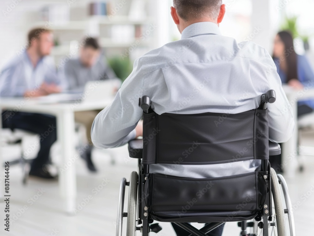 A man in a wheelchair sits in a room with other people, people with disabilities at work A man in a wheelchair sits in a room with other people, people with disabilities at work