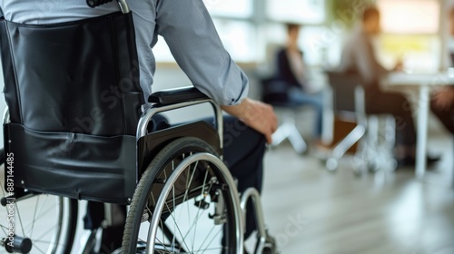 A man in a wheelchair sits in a room with other people, people with disabilities at work