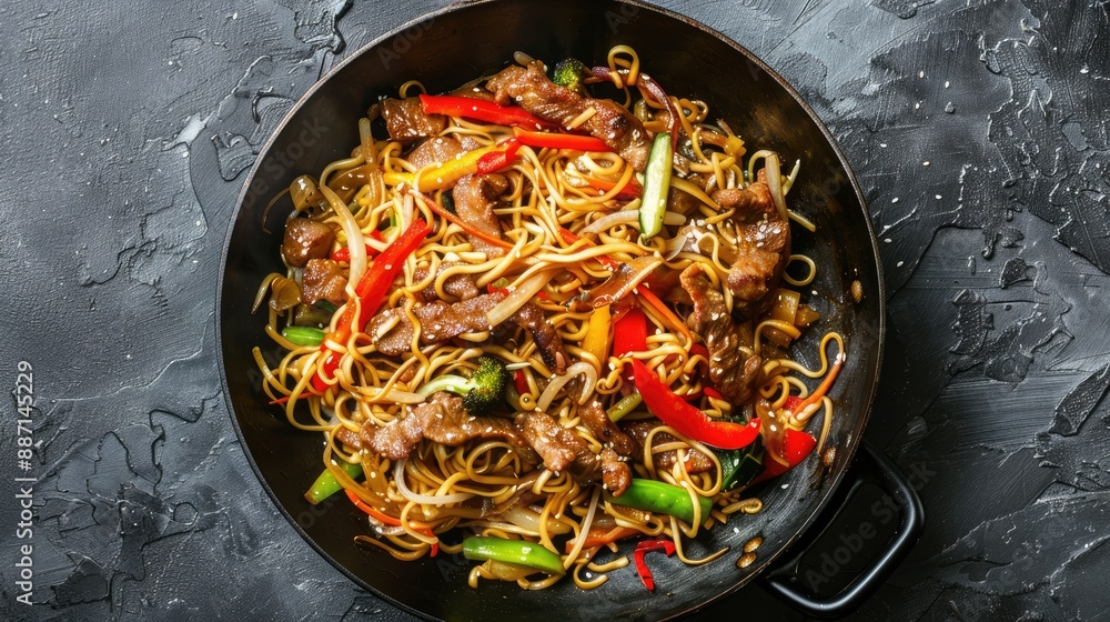 Close-up of delicious stir-fry noodles with meat and vegetables in wok on grey textured table, top view. Perfect for Asian food lovers. Close-up of delicious stir-fry noodles with meat and vegetables in wok on grey textured table, top view. Perfect for Asian food lovers.