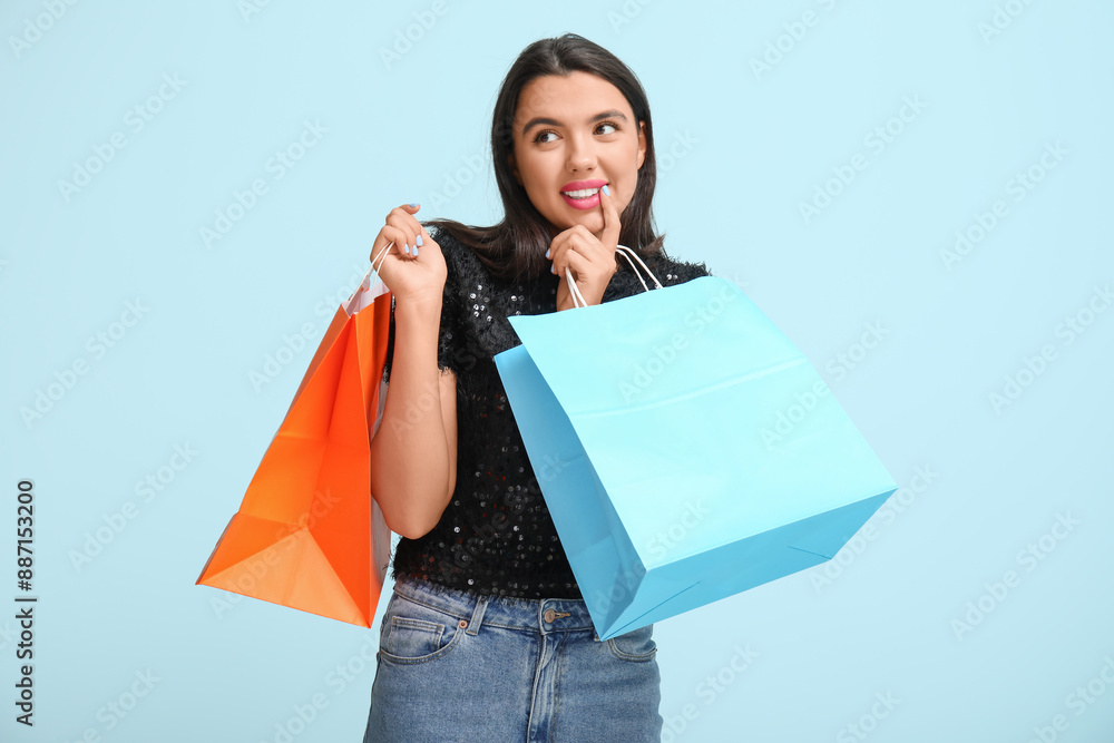 Beautiful young thoughtful woman with shopping bags on blue background Beautiful young thoughtful woman with shopping bags on blue background