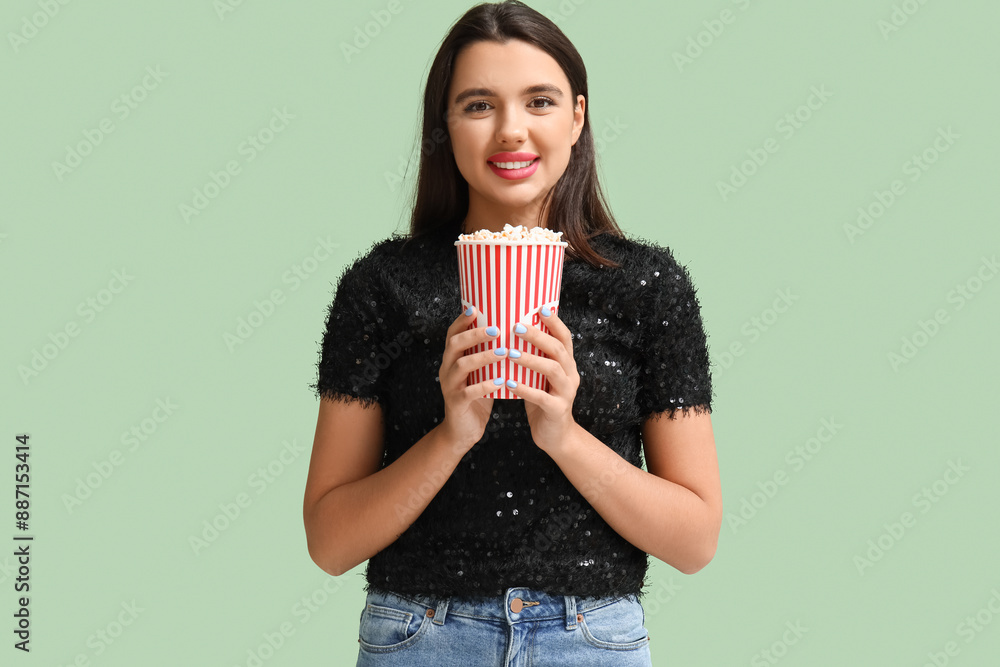 Beautiful young happy woman with bucket of popcorn on green background Beautiful young happy woman with bucket of popcorn on green background