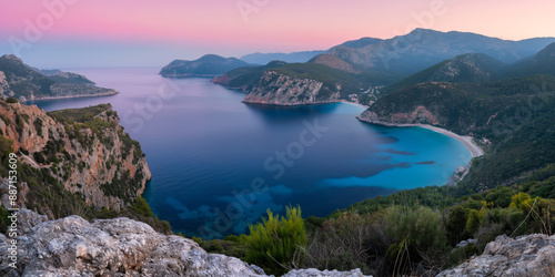 Breathtaking panoramic view of a coastal bay surrounded by mountains, with serene blue waters and a colorful sunset sky