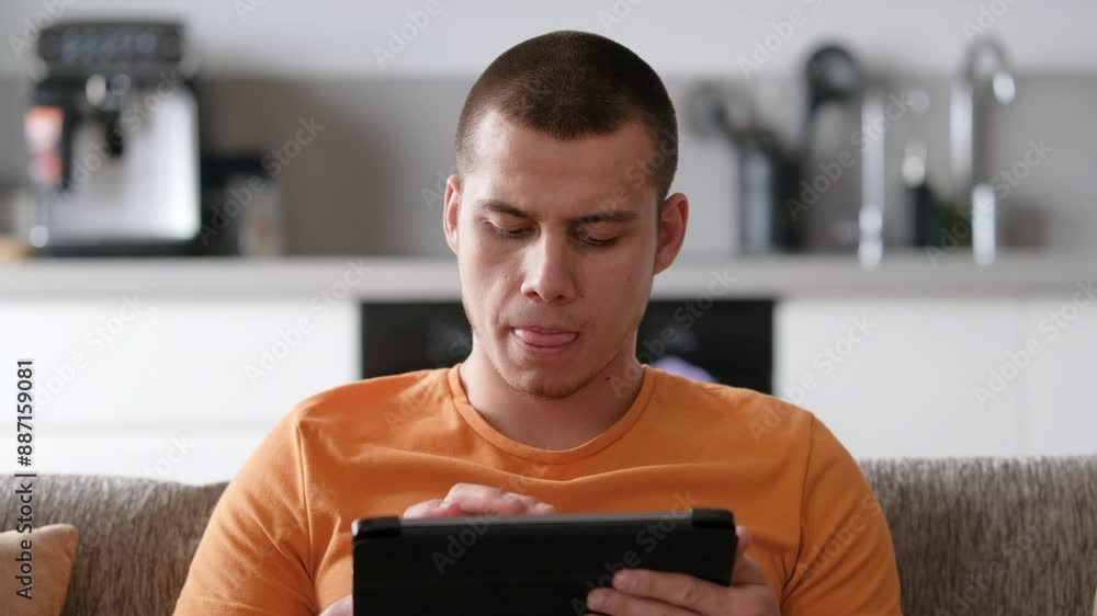Handsome young man surfing digital tablet in a cozy living room setting. Browsing internet website, using mobile applications, modern daily life, technology, social media concepts. 4k Handsome young man surfing digital tablet in a cozy living room setting. Browsing internet website, using mobile applications, modern daily life, technology, social media concepts. 4k
