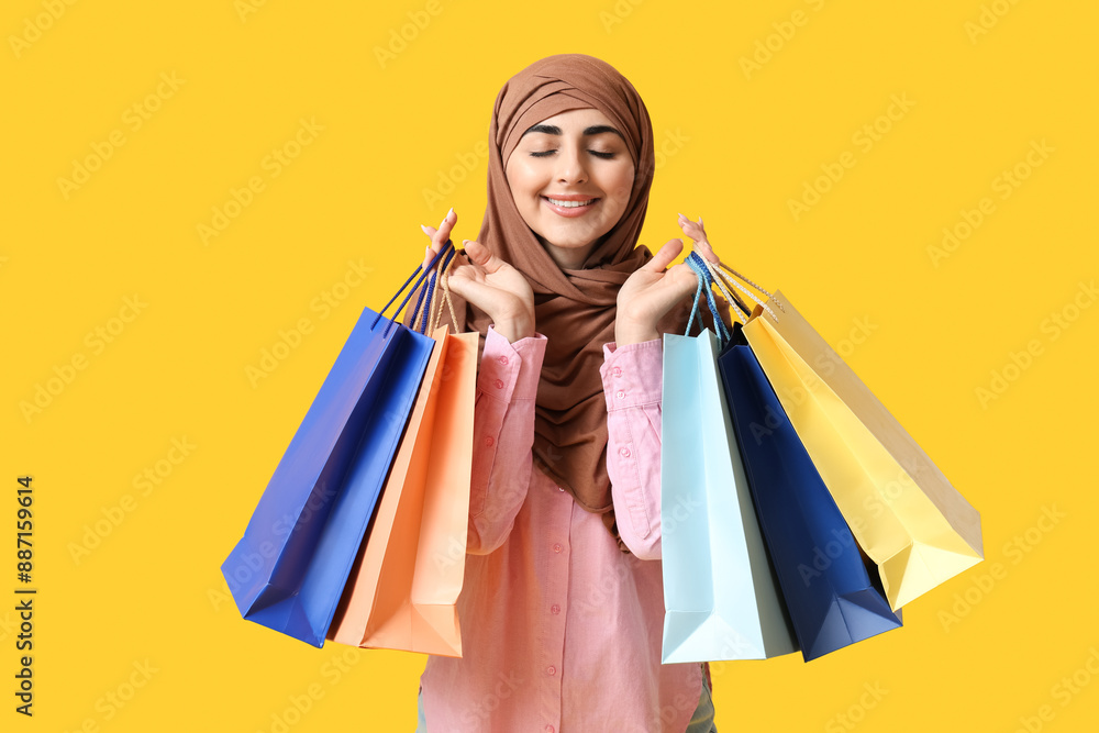 Happy Muslim woman with shopping bags on yellow background Happy Muslim woman with shopping bags on yellow background