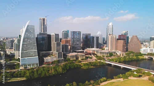 Stunning reverse zoom shot 4K aerial view of downtown Austin, TX, featuring skyscrapers, Lady Bird Lake, Congress Bridge, and Zilker Park on a sunny day photo