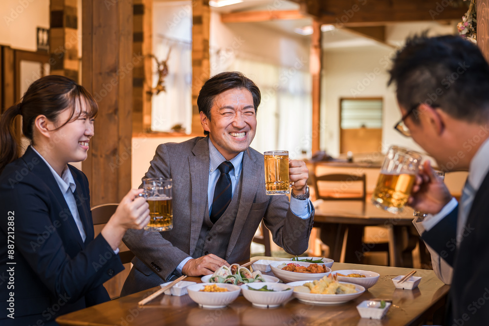 居酒屋で忘年会・新年会・飲み会・宴会をする仕事仲間・同僚・上司部下の男女
