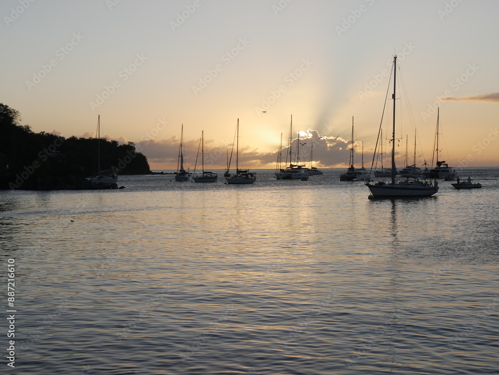 Sunset behing cloud in deshaies port, guadeloupe. Scenic landscape in Basse Terre with caribbean sea and sailboats Sunset behing cloud in deshaies port, guadeloupe. Scenic landscape in Basse Terre with caribbean sea and sailboats
