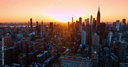 Golden light of setting sun lights the architecture of modern New York. Aerial perspective on beautiful metropolis at sunset.