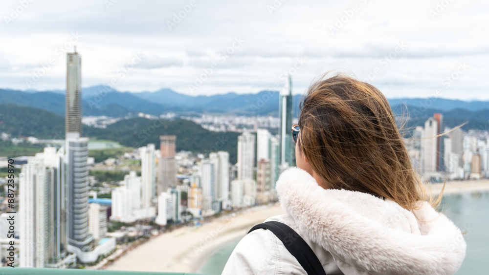 Young white brunette woman contemplating the view of the beachfront with large buildings in the background and the sea. Young white brunette woman contemplating the view of the beachfront with large buildings in the background and the sea.