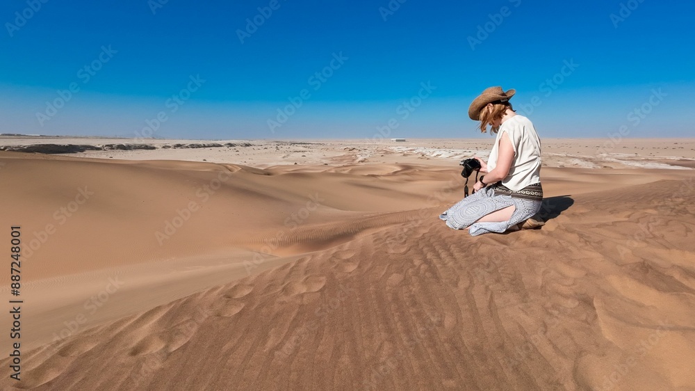 Lone woman traveling in a desert with sand dunes and a clear blue sky in Namibia, Africa Lone woman traveling in a desert with sand dunes and a clear blue sky in Namibia, Africa