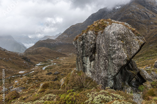 Large glacial erratic rock on the Routeburn Track, Fiordland National Park, New Zealand. The Route Burn river is on the valley floor in the background. photo