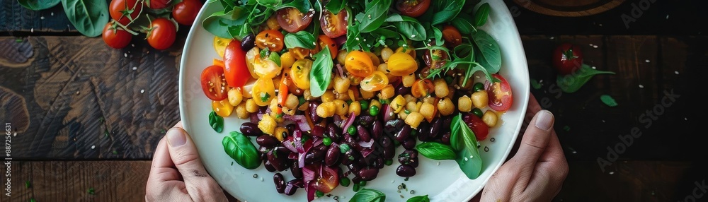 Colorful Mediterranean salad with fresh vegetables, chickpeas, and herbs on a rustic wooden table, held by hands. Colorful Mediterranean salad with fresh vegetables, chickpeas, and herbs on a rustic wooden table, held by hands.