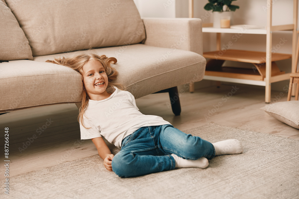 Little girl playing with colorful building blocks on the living room floor in front of a cozy couch Little girl playing with colorful building blocks on the living room floor in front of a cozy couch