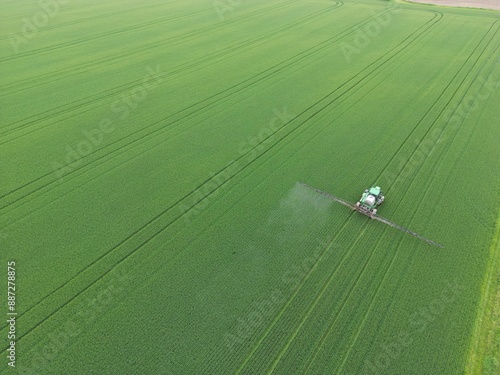 Tractor spraying a phytosanitary product on a huge green field - Tracteur qui épand un produit phytosanitaire sur un immense champ vert