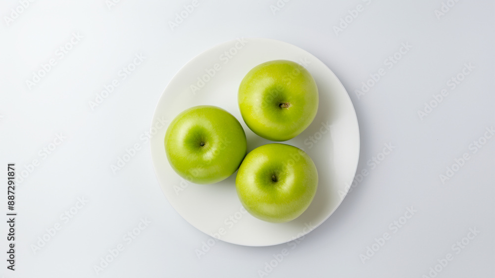 Three green apples on a white ceramic plate, fresh fruit on a white background Three green apples on a white ceramic plate, fresh fruit on a white background