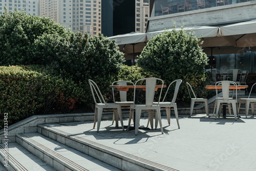 Outdoor cafe seating with metal chairs and wooden tables on a sunny day