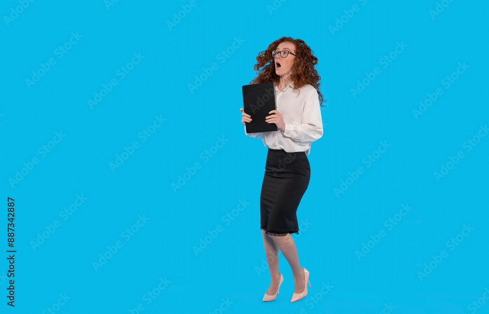 Woman Jumping in Surprise While Holding Folder on Blue Background Woman Jumping in Surprise While Holding Folder on Blue Background