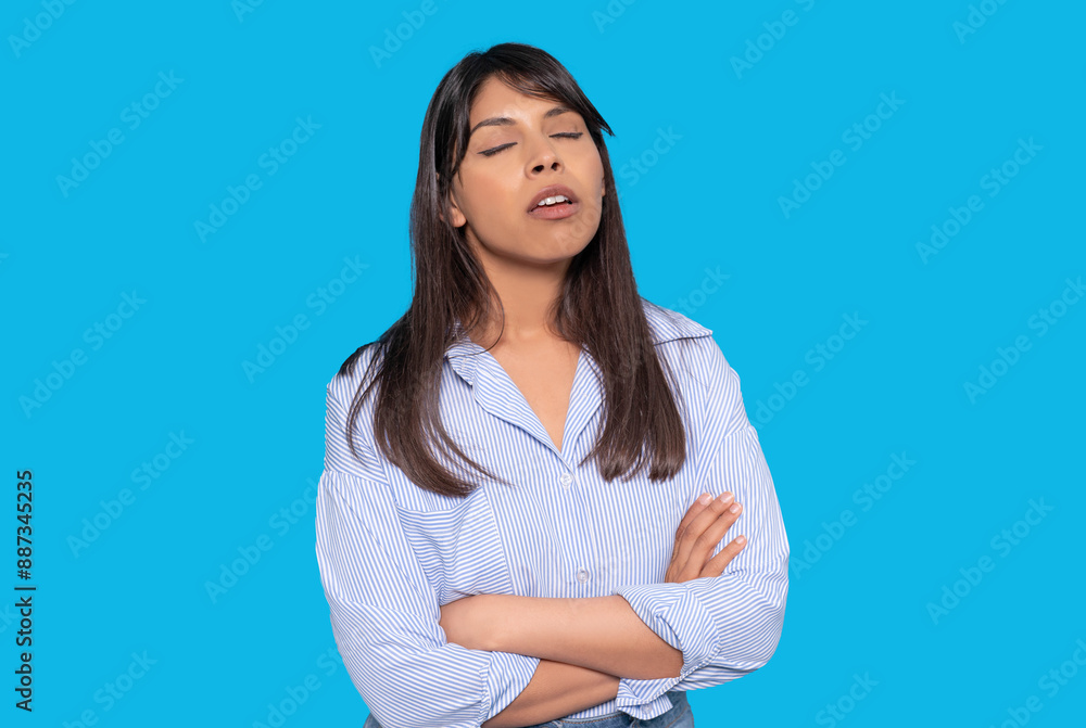 Woman With Brown Hair Wearing a Blue Striped Shirt Stands With Arms Crossed Against Blue Background Woman With Brown Hair Wearing a Blue Striped Shirt Stands With Arms Crossed Against Blue Background