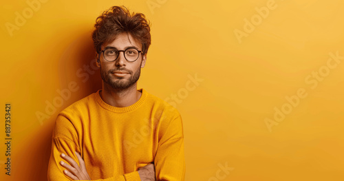 Attractive man in glasses and orange sweater pointing with hand smiling on colorful background, space for product, positive entrepreneur, advertising, looking at camera, promotional shot