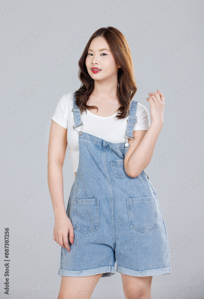 Portrait of Asian cute cheerful young girl wearing denim overalls ...