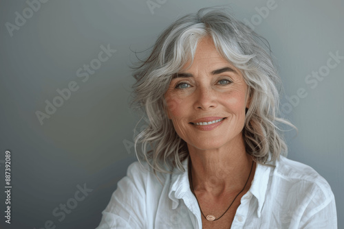 Elegant Senior Woman with Grey Hair Smiling in White Shirt Over Gray Background, Beautiful Old Lady Portrait Healthy Skin Care Beauty