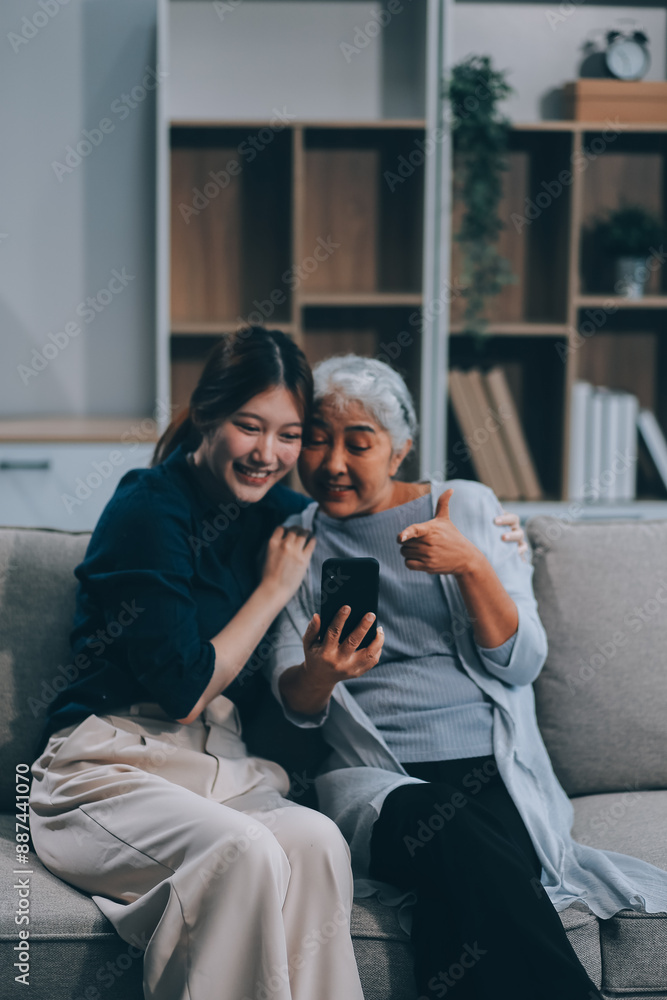 Cheerful mother and pretty teenager kid relaxing at cozy home, using mobile phone for Internet communication, resting on sofa with digital gadget, enjoying leisure, looking at camera Cheerful mother and pretty teenager kid relaxing at cozy home, using mobile phone for Internet communication, resting on sofa with digital gadget, enjoying leisure, looking at camera