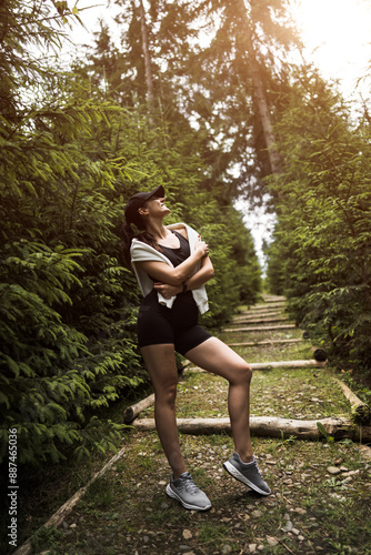 A sporty woman in a cap poses against the background of houses in the mountains. The concept of sports and recreation. Morning exercises © Darius