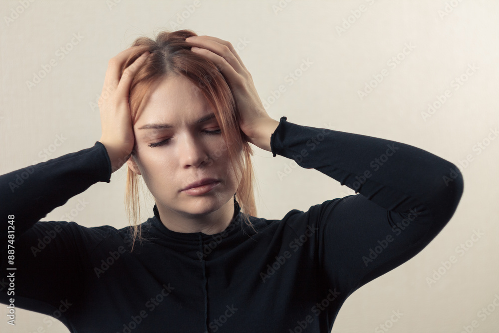 Girl with a headache: close-up, the girl holds her temples, her facial expression conveys discomfort Girl with a headache: close-up, the girl holds her temples, her facial expression conveys discomfort
