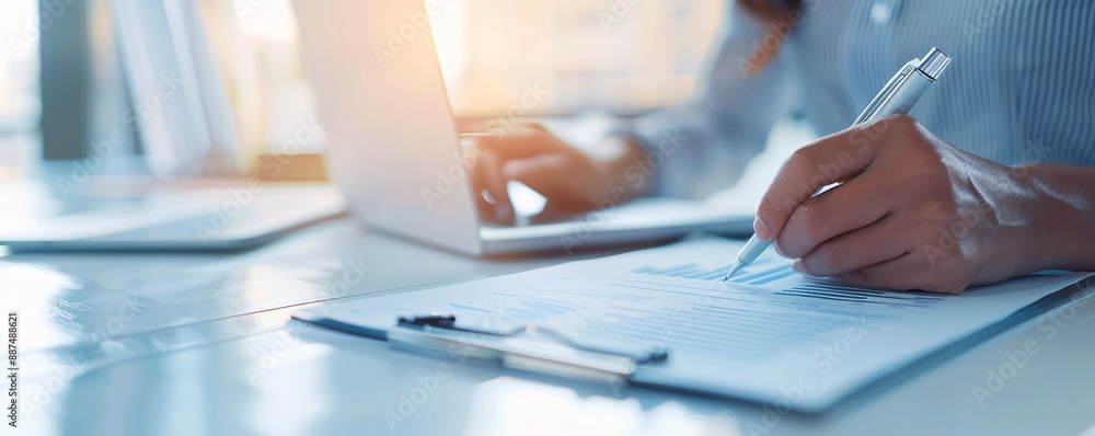 A close-up of financial documents, charts, and a consultant laptop on a modern desk. The consultant hands are visible as they write notes, emphasizing professional financial consulting services. A close-up of financial documents, charts, and a consultant laptop on a modern desk. The consultant hands are visible as they write notes, emphasizing professional financial consulting services.