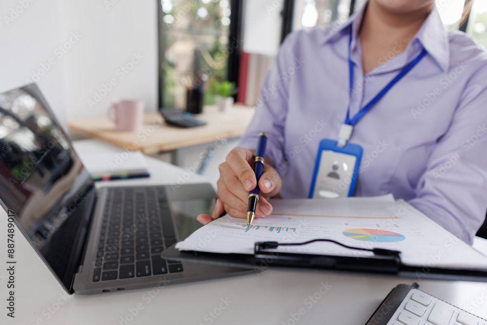 Close up of business woman or accountant hand holding pen working on calculator to calculate business data, accountancy document and laptop computer at office, business concept Close up of business woman or accountant hand holding pen working on calculator to calculate business data, accountancy document and laptop computer at office, business concept