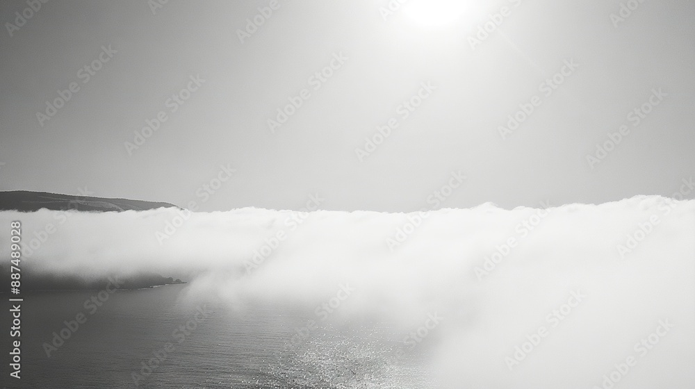 Fototapeta premium A monochrome image of a vast expanse of water shrouded in mist, with a mountain fading into the haze in the background