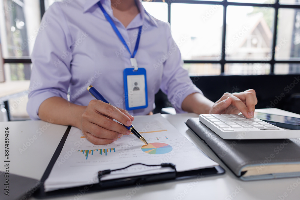 Fototapeta premium Close up of business woman or accountant hand holding pen working on calculator to calculate business data, accountancy document and laptop computer at office, business concept