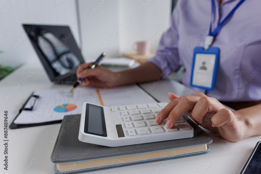 Close up of business woman or accountant hand holding pen working on calculator to calculate business data, accountancy document and laptop computer at office, business concept Close up of business woman or accountant hand holding pen working on calculator to calculate business data, accountancy document and laptop computer at office, business concept