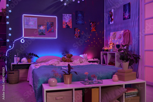 Background image of girls room interior with pink and purple neon lights over comfortable bed and fluorescent art copy space photo