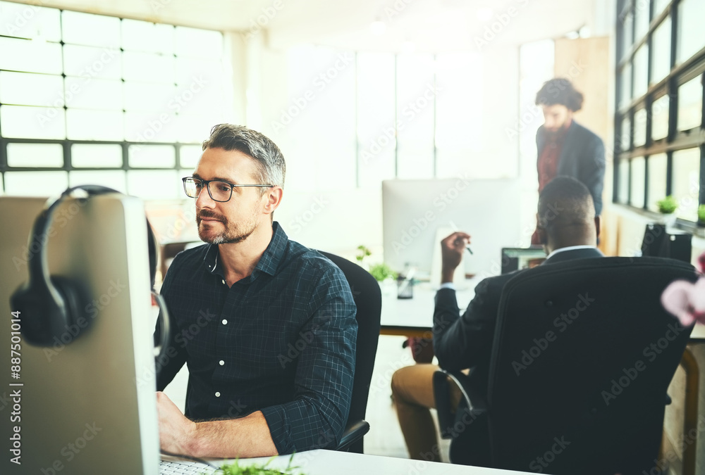 Mature, man and computer in office as colleagues in digital agency as brand designer. Male person, smile and tech in coworking space with team, collaboration and deadline for confidence in business Mature, man and computer in office as colleagues in digital agency as brand designer. Male person, smile and tech in coworking space with team, collaboration and deadline for confidence in business